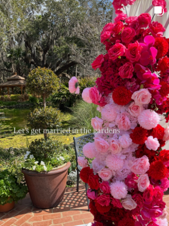 Pink and red floral column styled for a garden wedding ceremony.