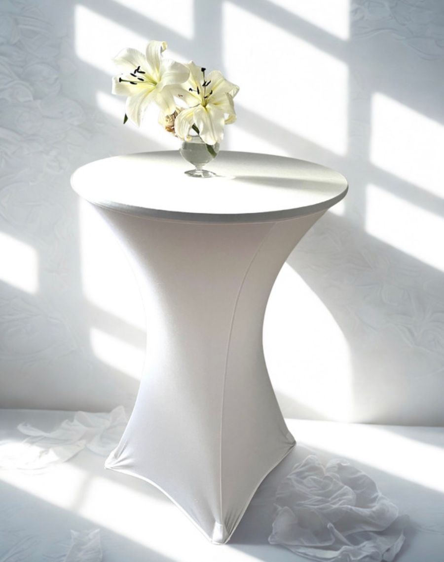 A round table draped with a crisp white floor-length linen.