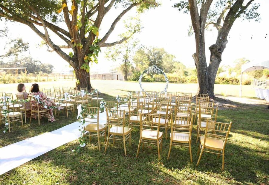 A tented wedding setup with chiavari chairs and white linens.