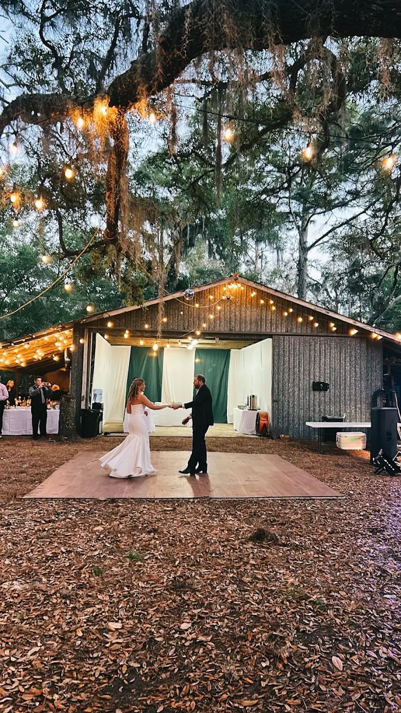 Bride and groom on an outdoor dance floor with surrounding string lights
